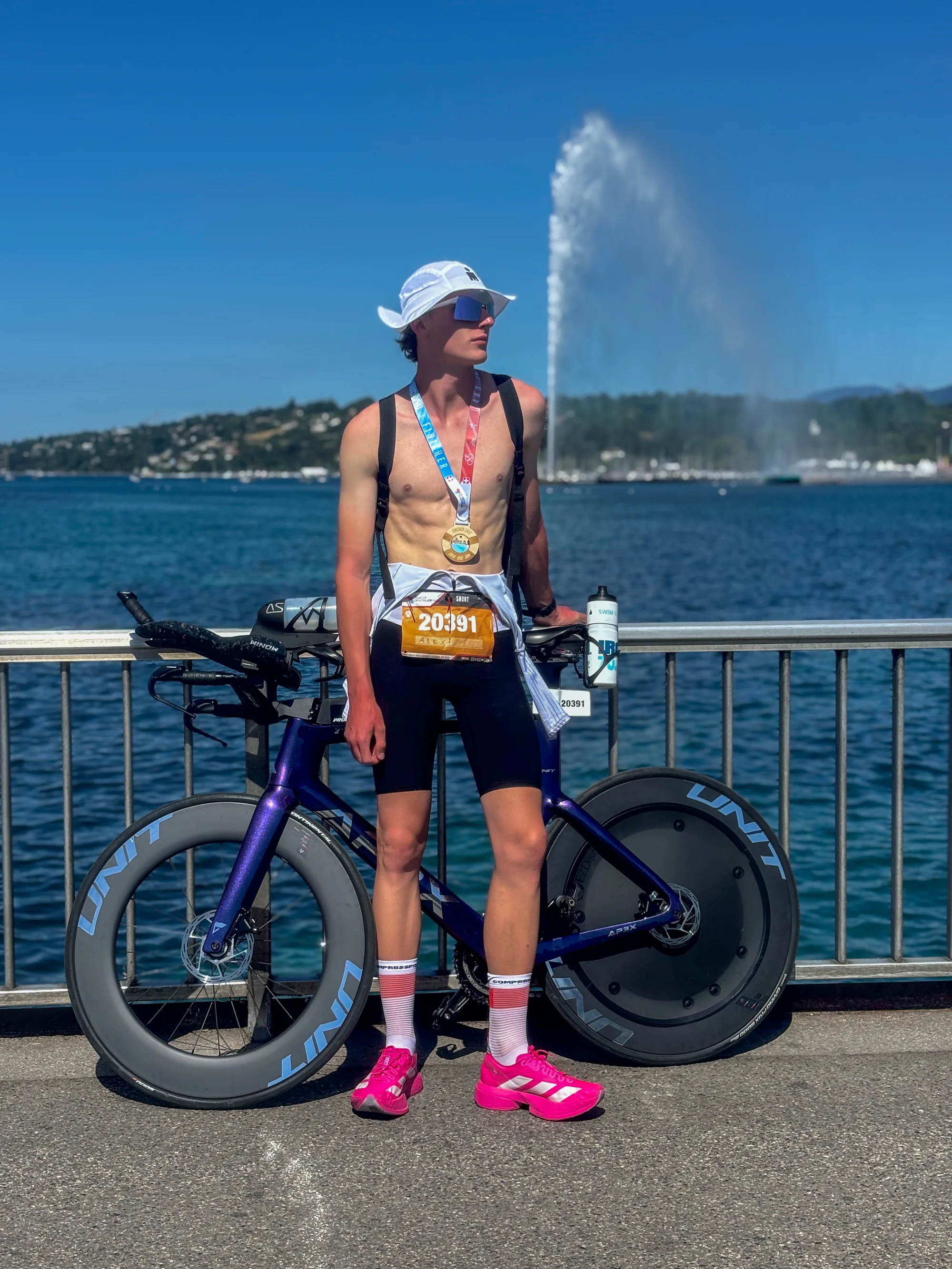 Avec une médaille de finisher et un vélo au bord de l’eau.